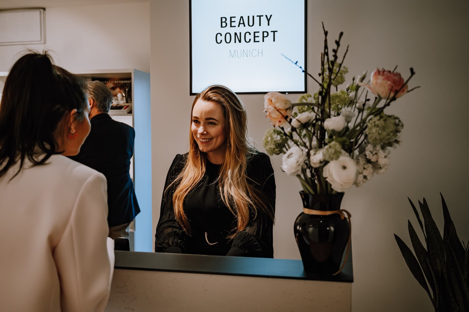 Julia Modery begrüßt eine Kundin am Empfangstresen des Kosmetikstudios Beauty Concept Munich in München Au-Haidhausen